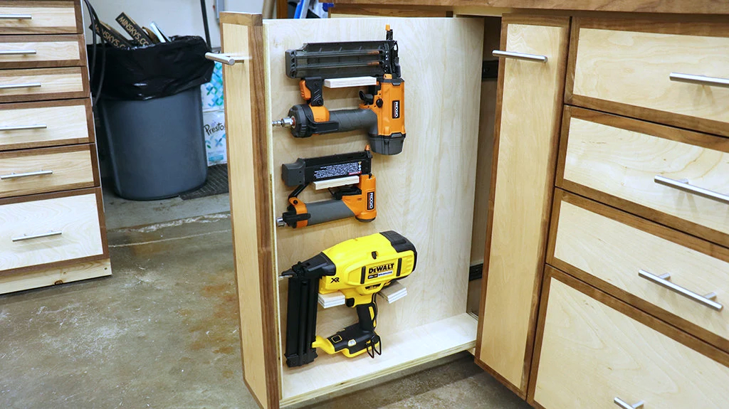 Nail guns stored in a shop storage base cabinet drawer