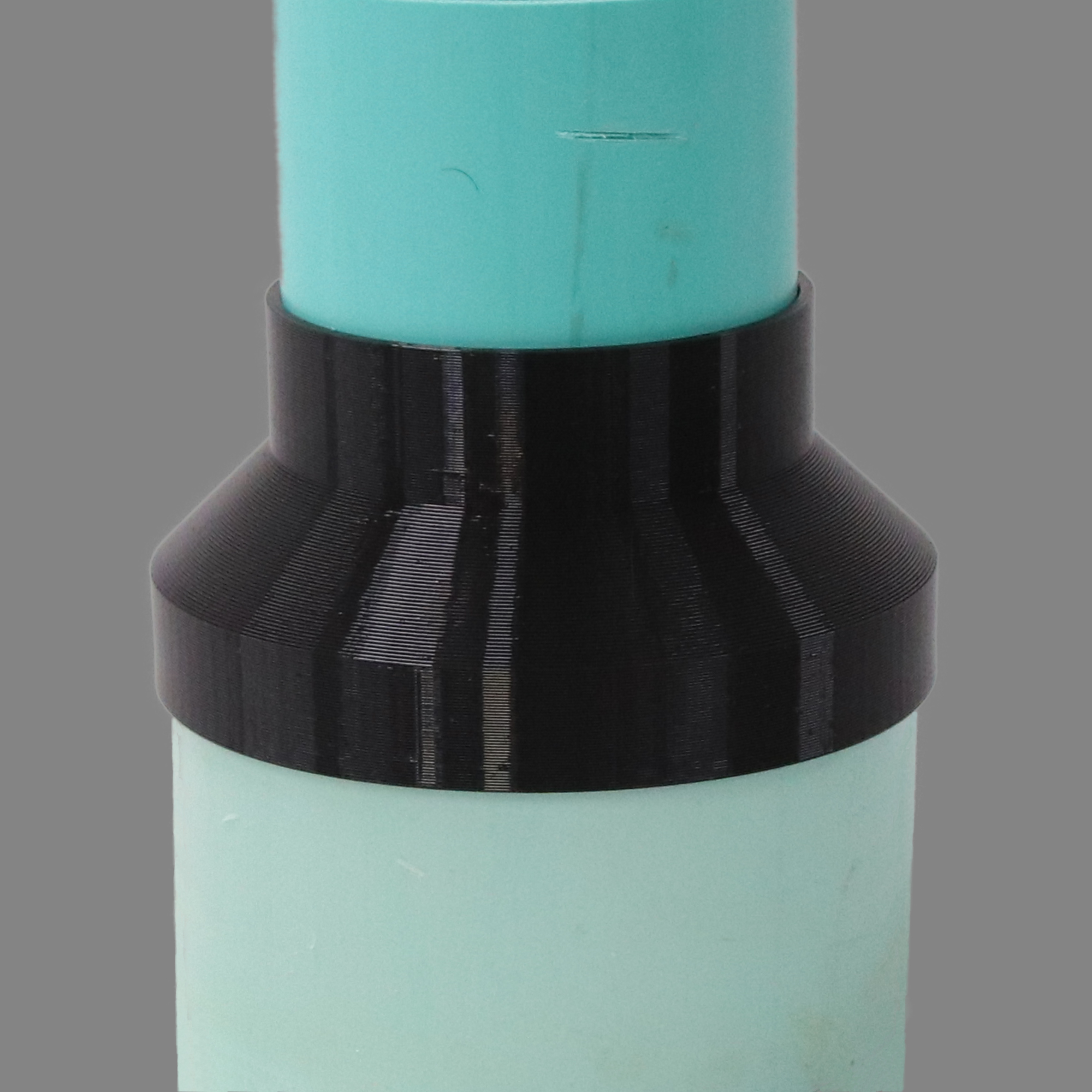 Black PETG dust collection adapter connecting 6 inch SDR35 PVC to 4 inch SDR35 PVC, shown installed in a shop dust collection hose line