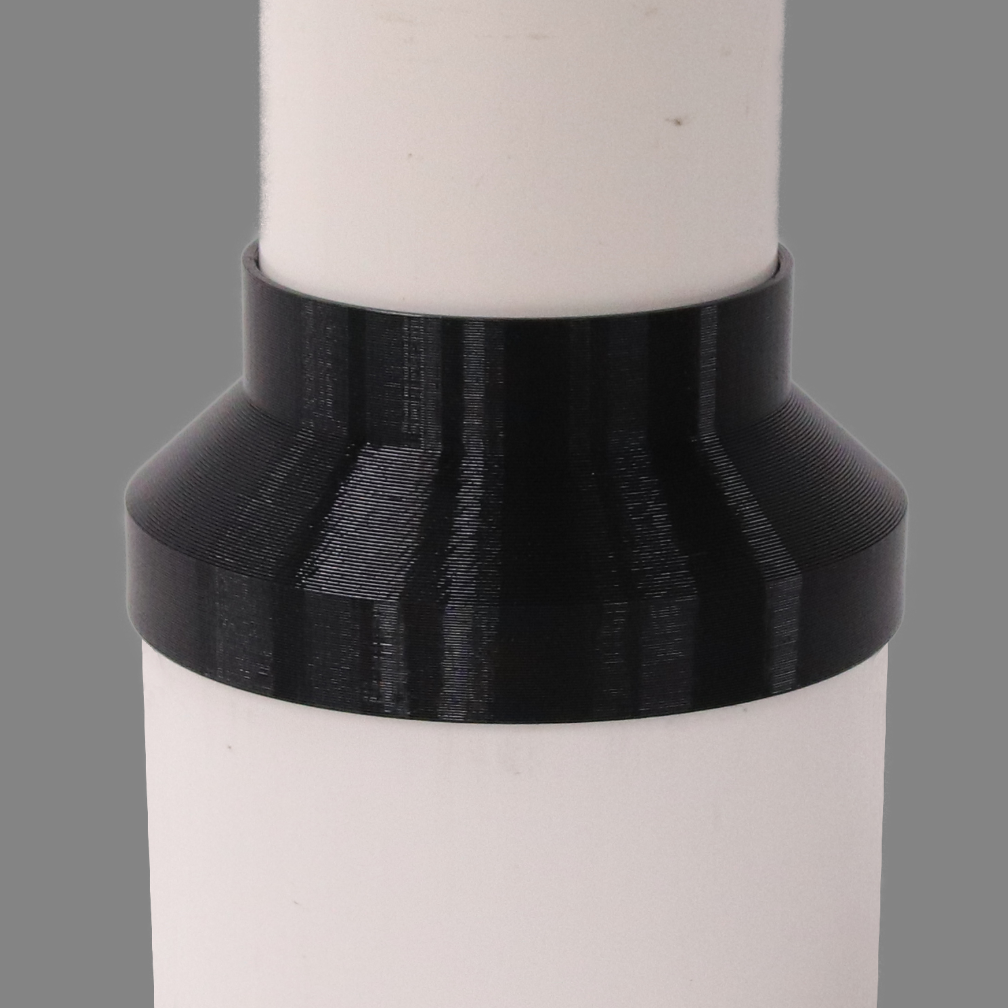 Black PETG dust collection adapter connecting 6 inch SCH40 PVC to 4 inch SCH40 PVC, shown installed in a shop dust collection hose line
