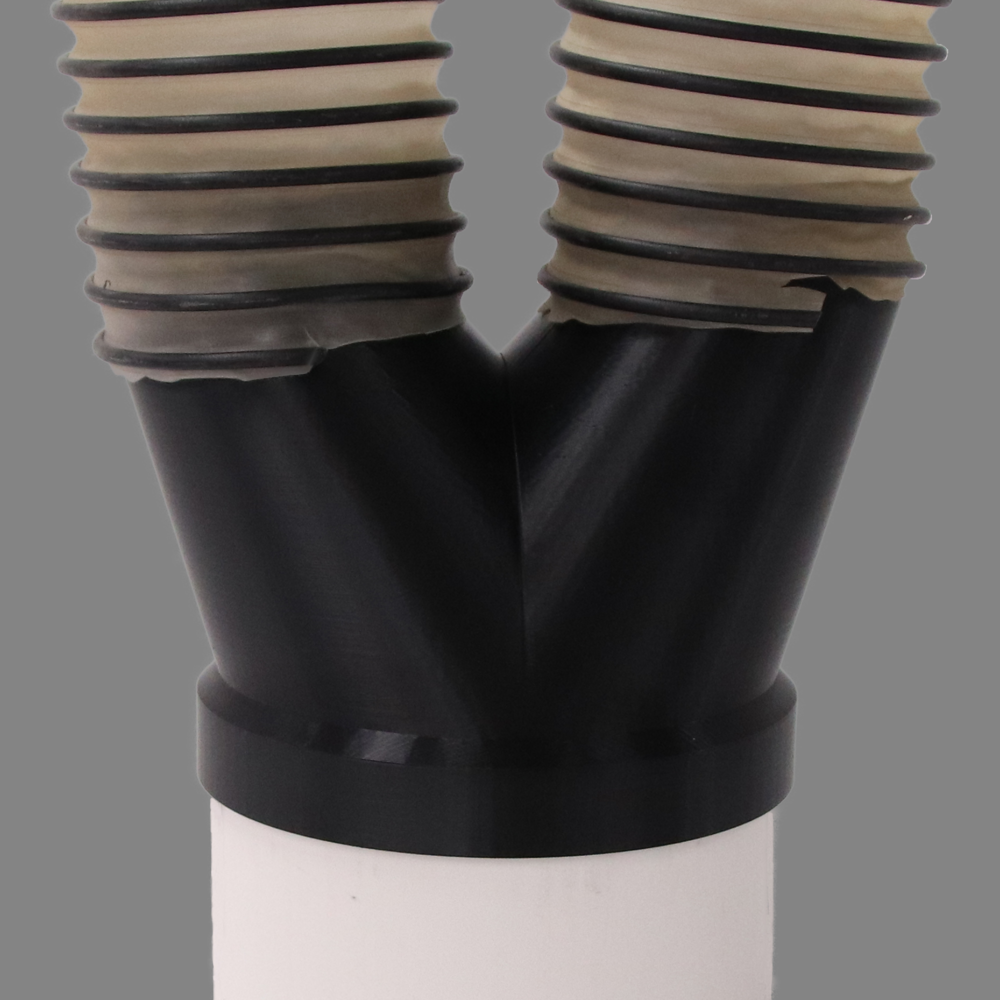 Black PETG dust collection adapter connecting 6 inch SCH40 PVC to dual 4 inch flex hose outlets, shown installed in a shop dust collection hose line