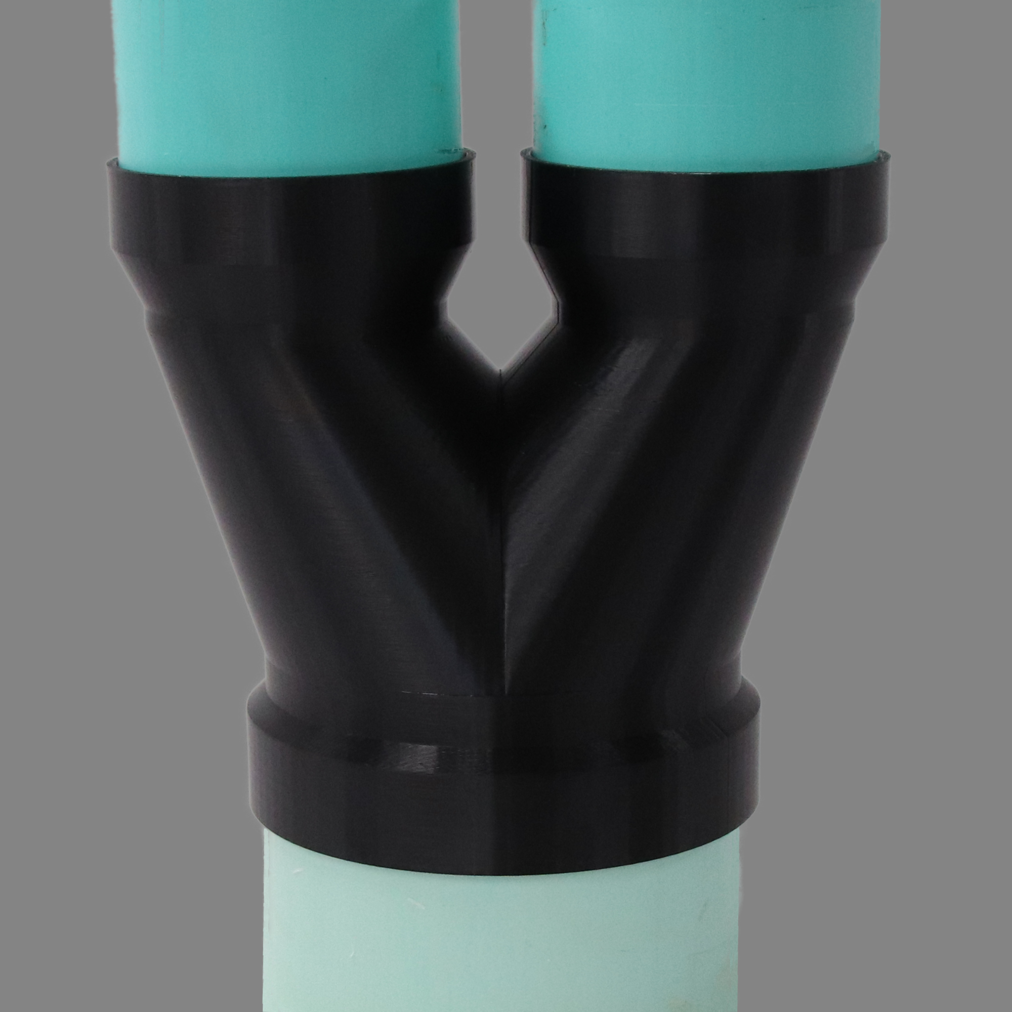 Black PETG dust collection adapter connecting 6 inch SDR35 PVC to dual 4 inch SDR35 PVC outlets, shown installed in a shop dust collection hose line